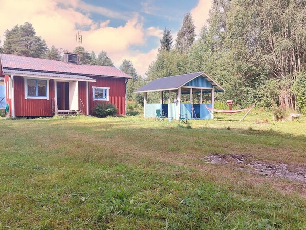 A red house with a porch and a blue shed with a roof. - 3 Person Holiday Home in Graninge (Graninge)