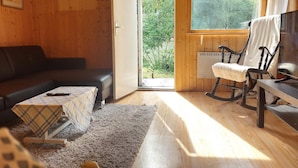L’intérieur d’un chalet en bois chaleureux et accueillant, avec un canapé, un fauteuil à bascule et une table.