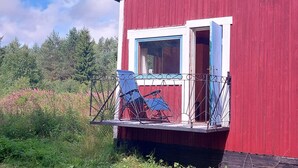 Un bâtiment en bois rouge, doté d’un balcon et d’une fenêtre.