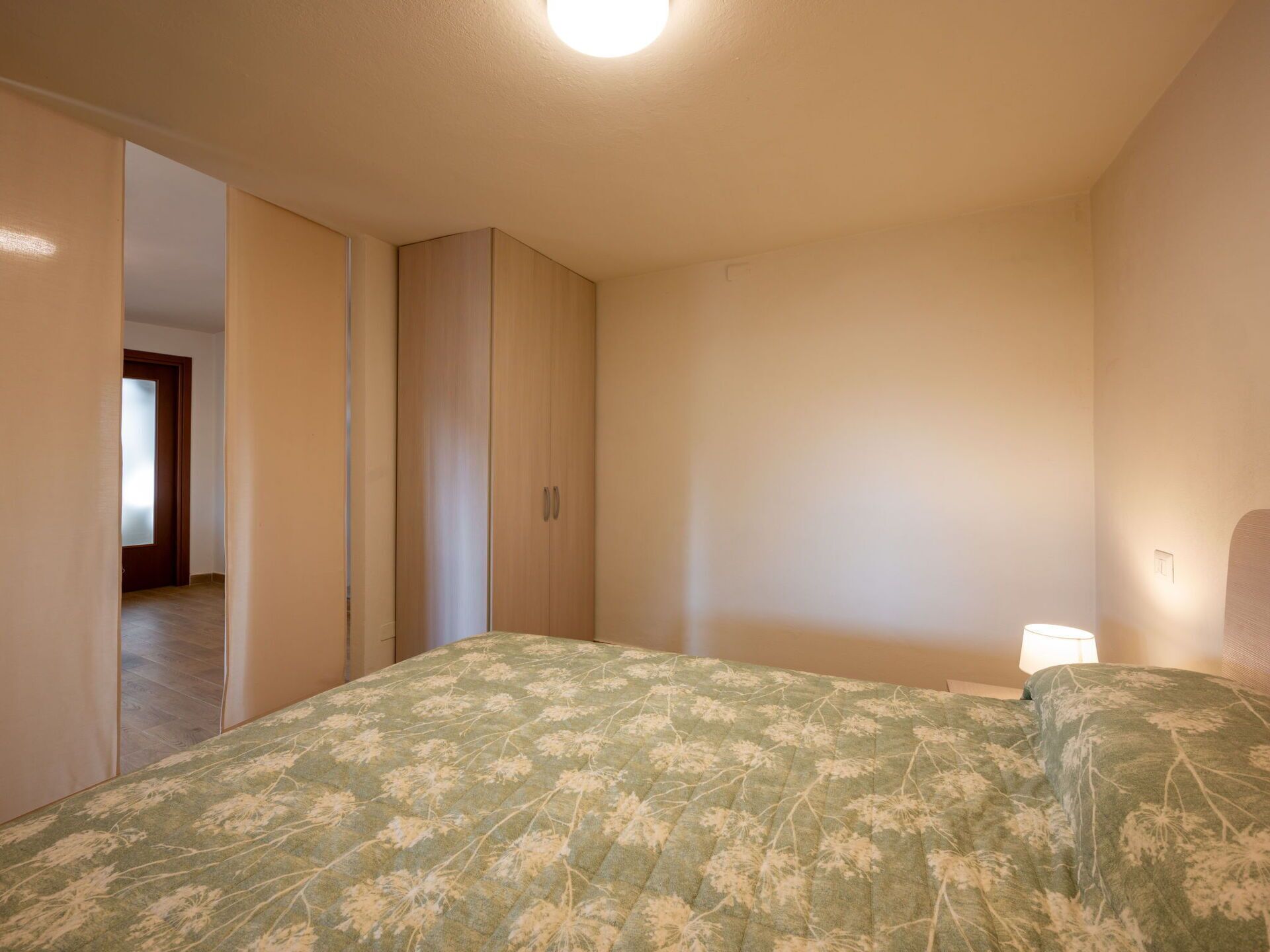Ein Schlafzimmer mit einem Bett, einem Kleiderschrank und einer Tür zu einem anderen Raum.