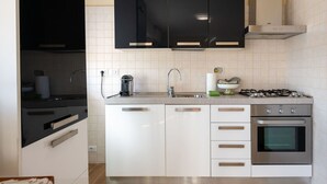 Eine moderne Küche mit schwarzen Schränken, einer Edelstahlspüle, einem Gasherd und einem Backofen.
