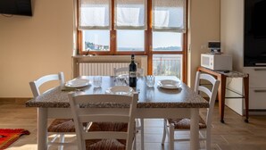 Ein Essbereich mit einem Tisch für vier Personen, einer Weinflasche und Meerblick durch große Fenster.