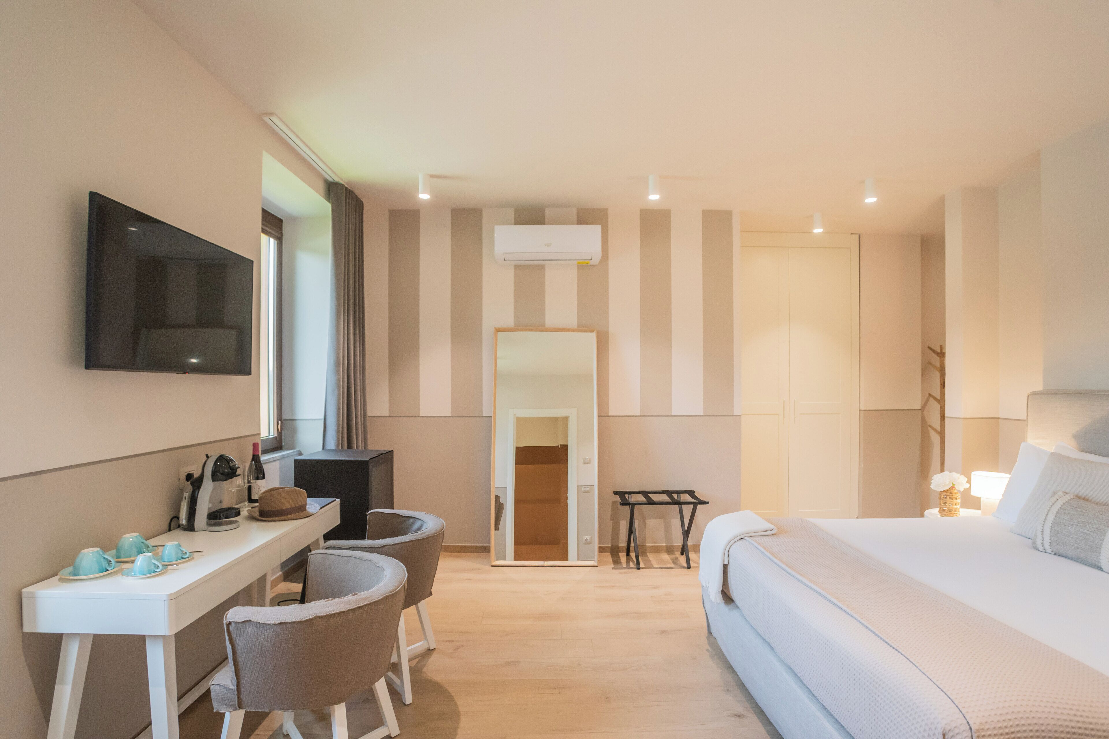 Ein Hotelzimmer mit einem Bett, einem Schreibtisch mit Stühlen, einem Fernseher und einem Kleiderschrank.