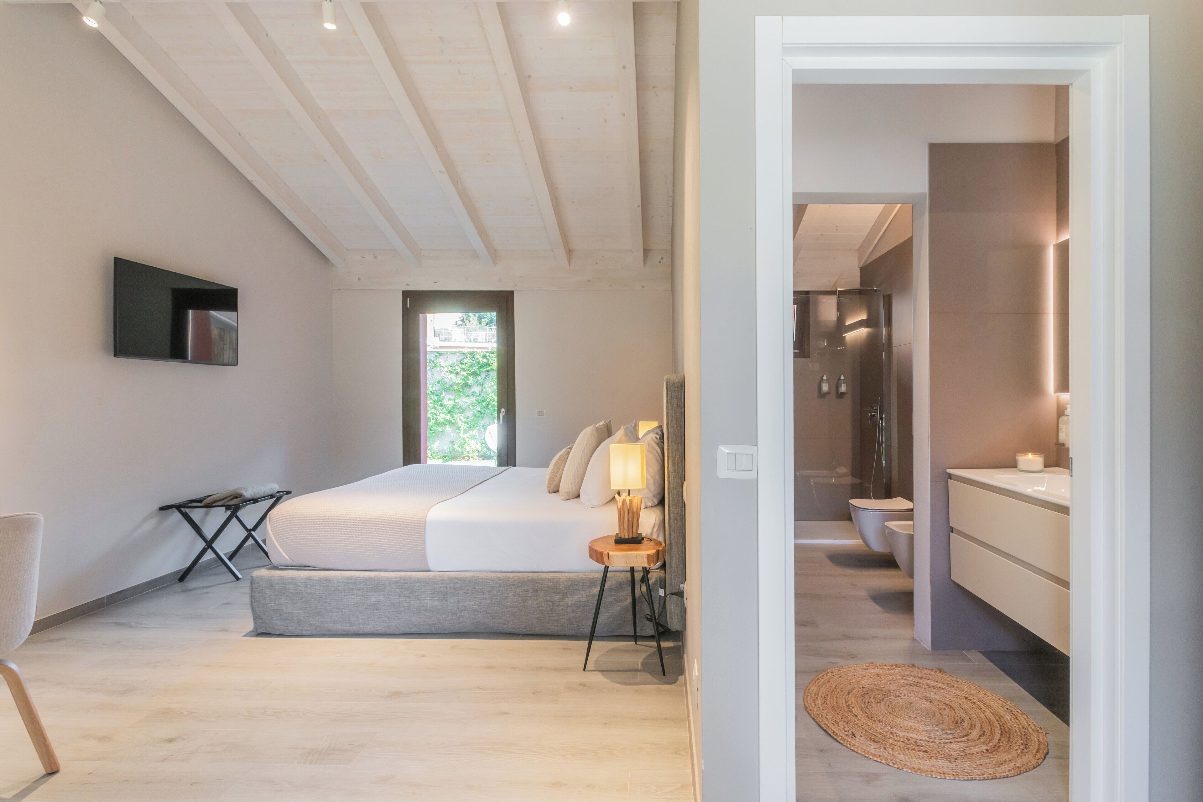 A modern bedroom with a large bed, bedside table, and a TV mounted on the wall.