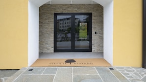 A hotel entrance with a stone facade, a yellow wall, and a black door. - Villa Il Platano (Como)