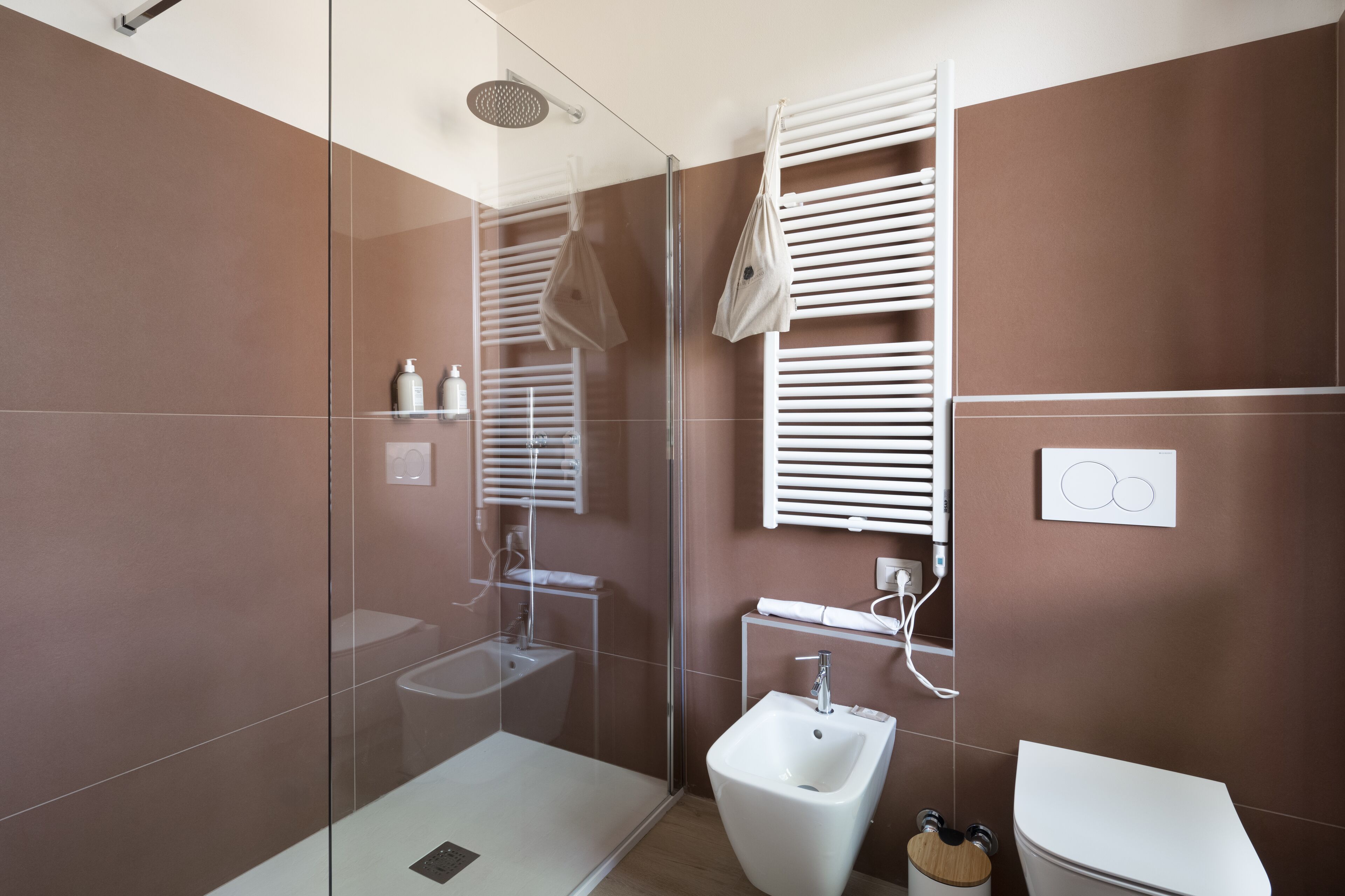 A modern bathroom with a glass-enclosed shower, a white sink, and a toilet.