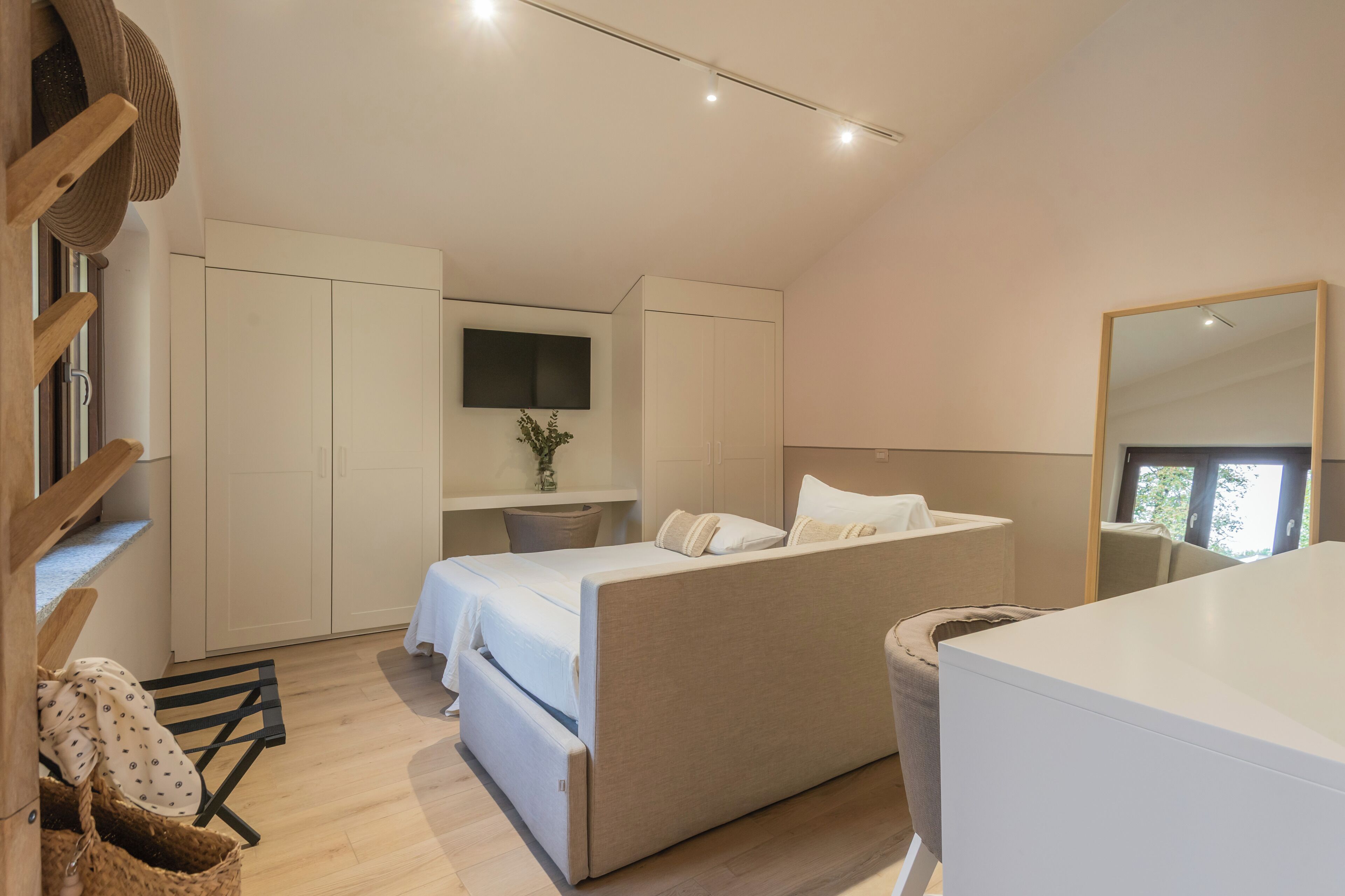 Une chambre à coucher moderne avec un lit, un téléviseur fixé au mur et un grand miroir.