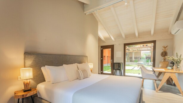 A modern hotel room with a large bed, a desk, and a view of the outdoor area. - Villa Il Platano (Como)
