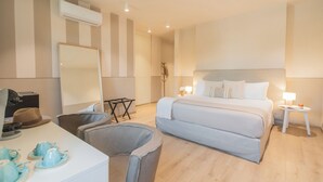 A modern hotel room with a large bed, bedside lamps, a desk with a computer, and a dining area with blue tableware. - Villa Il Platano (Como)