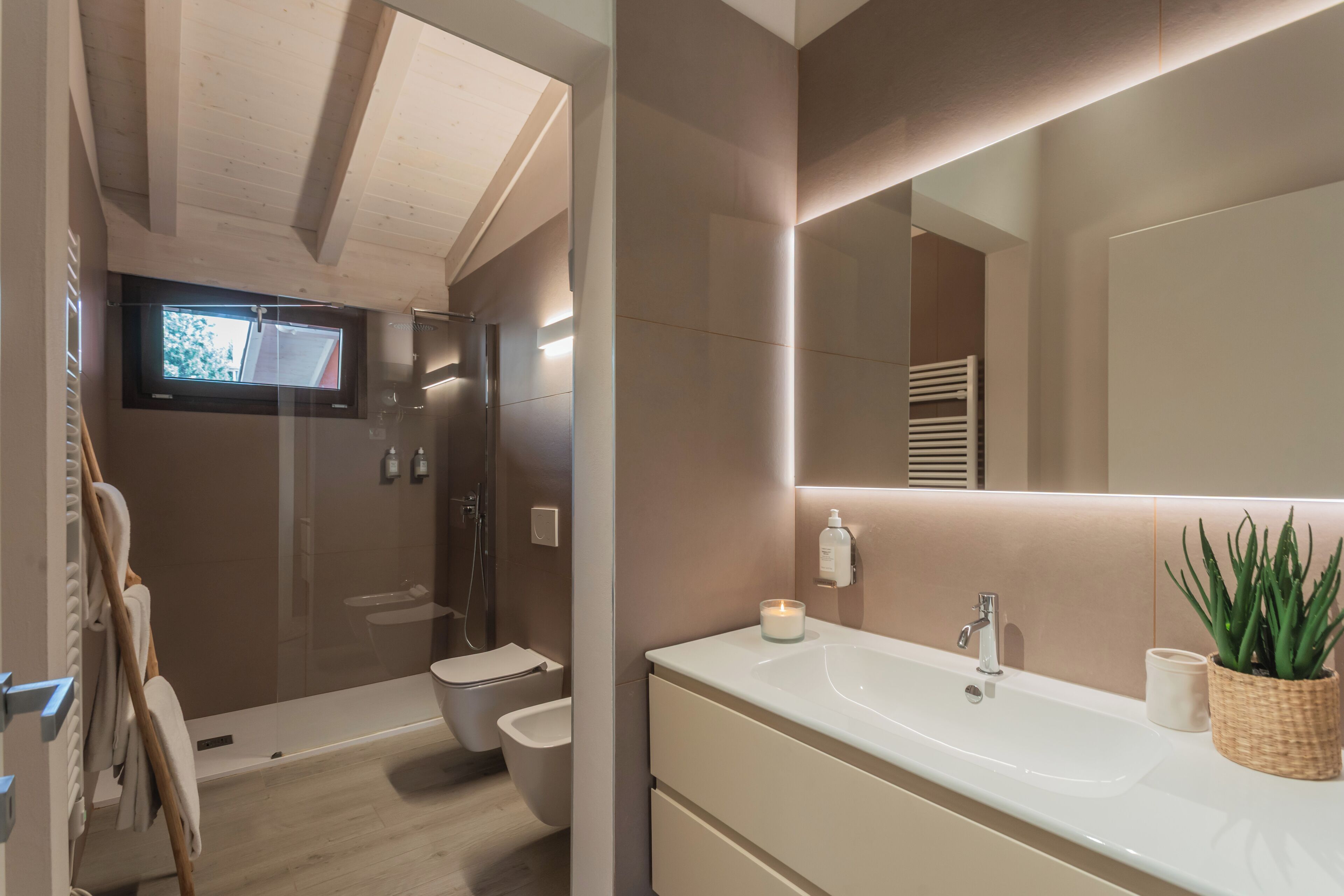 Un baño moderno con un espejo grande, un lavabo y una zona de ducha.