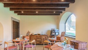 A cozy dining area with wooden tables and chairs, a stone fireplace, and a kitchen area with a coffee machine. - Villa Il Platano (Como)