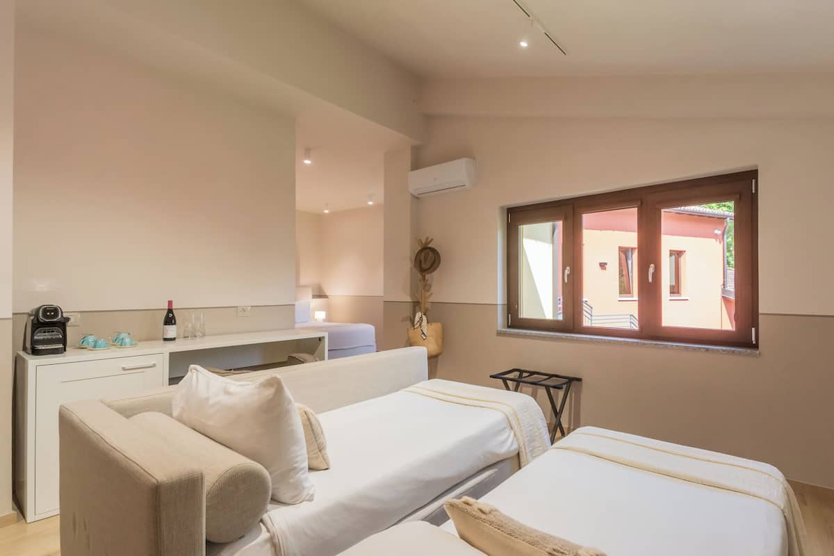 A hotel room with two beds, a desk, and a window with a view of the outside.