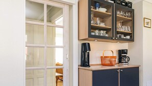 Une petite cuisine équipée d’une machine à café, d’un panier et d’un placard contenant de la vaisselle.