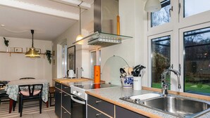 Une cuisine moderne dotée d’un four encastré, d’un évier à deux bacs et d’un meuble avec une porte en verre.