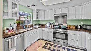 A modern kitchen with white cabinets, stainless steel appliances, and a large window.