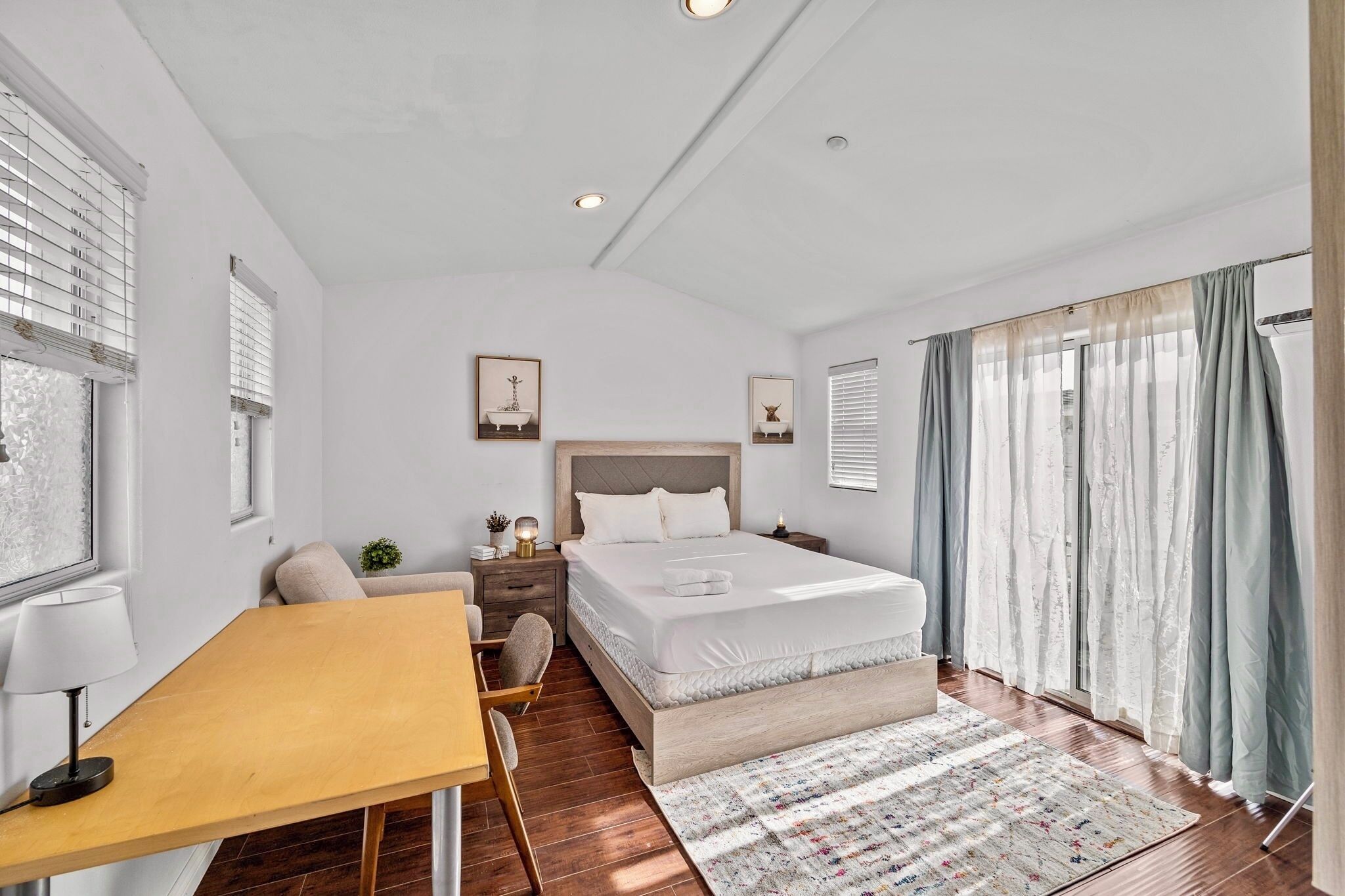 A modern bedroom with a large bed, bedside tables, a desk, and a chair.