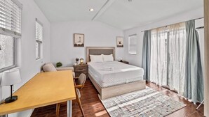 A modern bedroom with a large bed, bedside tables, a desk, and a chair.