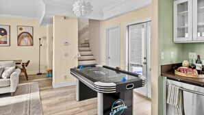 A modern living room with a foosball table, a sofa, and a dining area with a coffee table.
