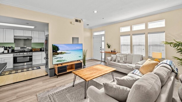 A spacious living area with a large flat-screen TV, a wooden coffee table, and a beige sofa.