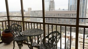 A balcony with a wrought iron table and chairs, potted plants, and a view of a cityscape with buildings. - Stylish Atlanta Retreat! (Atlanta)