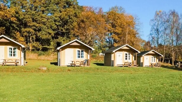 Three small cabins with picnic tables in a grassy field, surrounded by trees. - Holiday Home Near Fishing Area (Hoor)