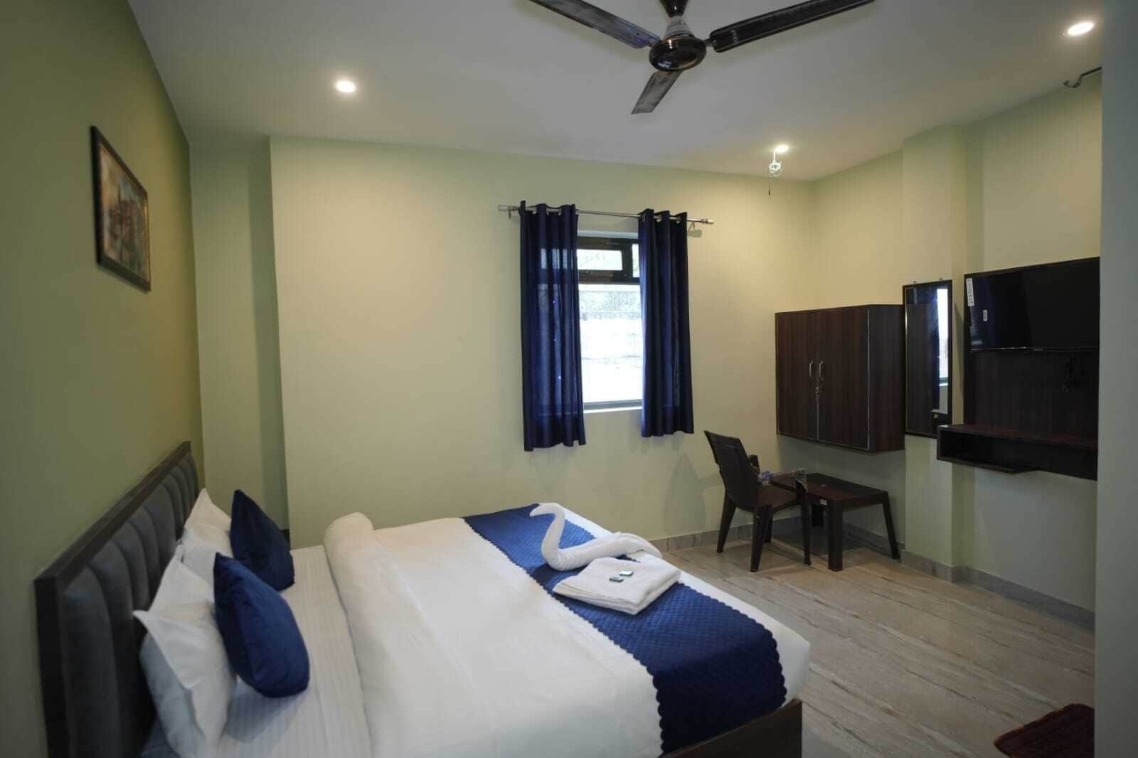 A hotel room with a bed, a desk, a chair, a TV, and a ceiling fan.