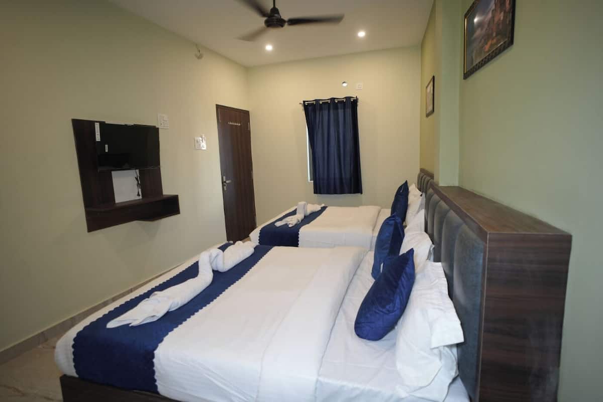 A hotel room with two beds, a ceiling fan, a small shelf, a door, and a window with curtains.