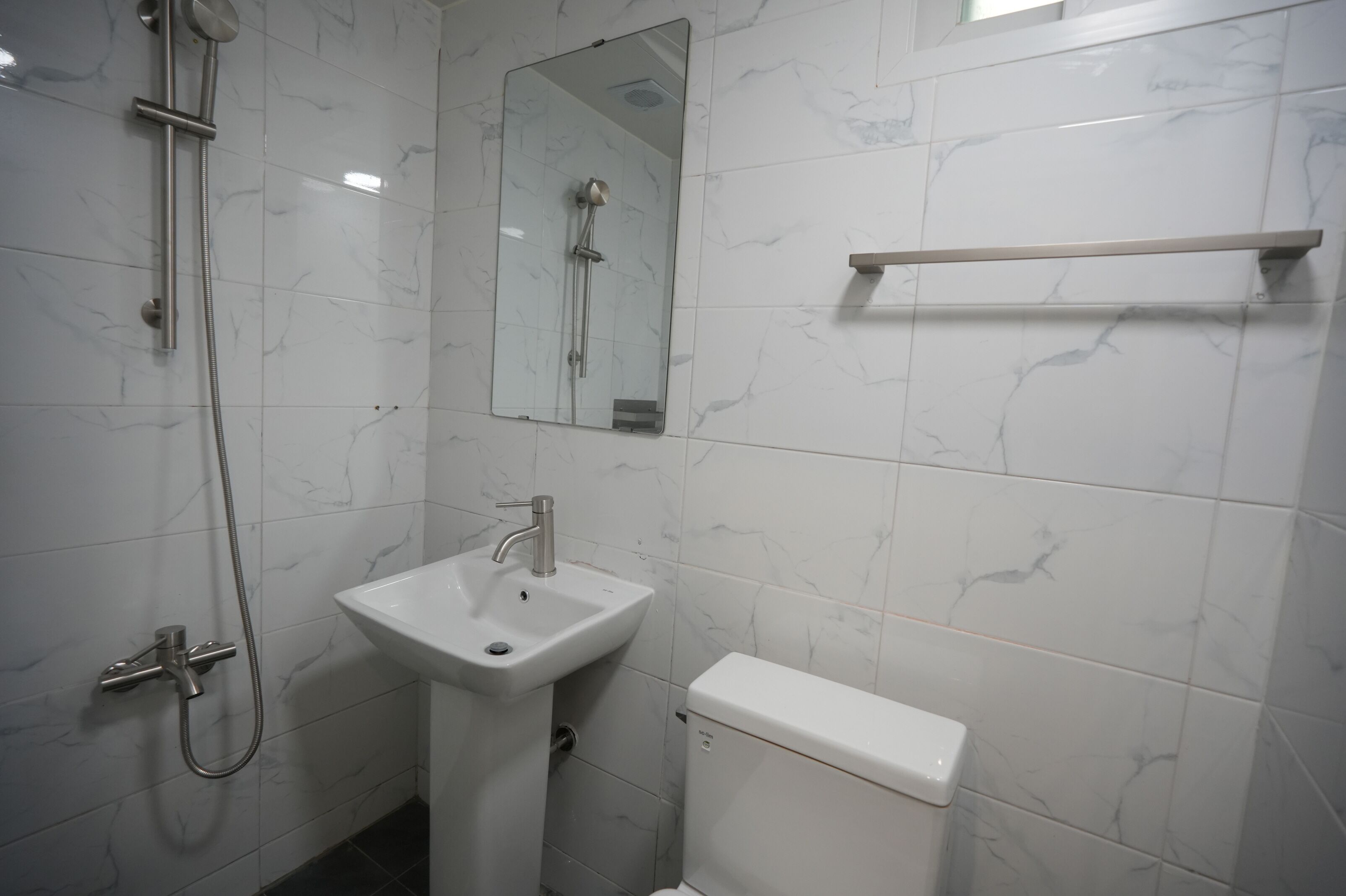 Un baño con ducha, lavabo, inodoro y espejo.