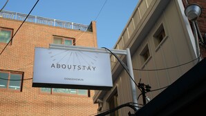 Een bord met 'AboutStay', met in de achtergrond een duidelijk zicht op een bakstenen gebouw.