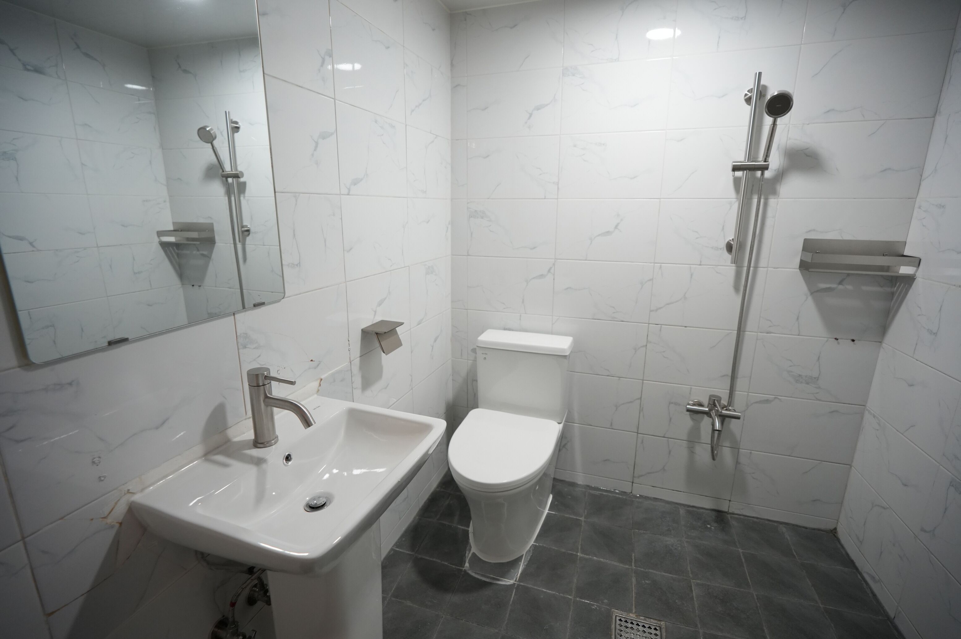 Un baño con lavamanos, inodoro y ducha blancos.