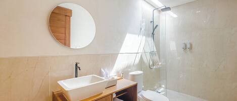 A modern bathroom with a large sink, toilet, and shower.