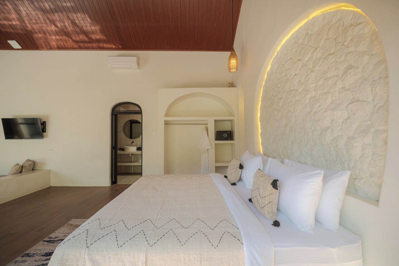 Een slaapkamer met een bed, een televisie, een kledingkast en een deur naar een badkamer.