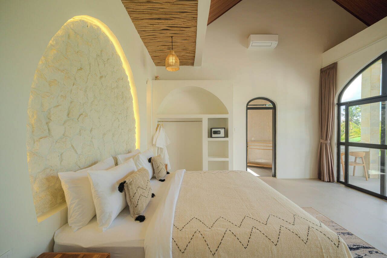 Ein Schlafzimmer mit einem großen Bett, einer Steinwand, einer Holzbalkendecke und einem großen Fenster.
