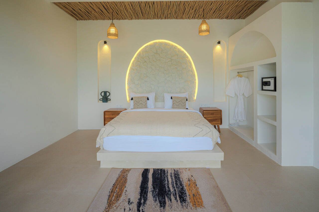 A modern bedroom with a large bed, two bedside tables, a circular wall feature, and a built-in wardrobe.