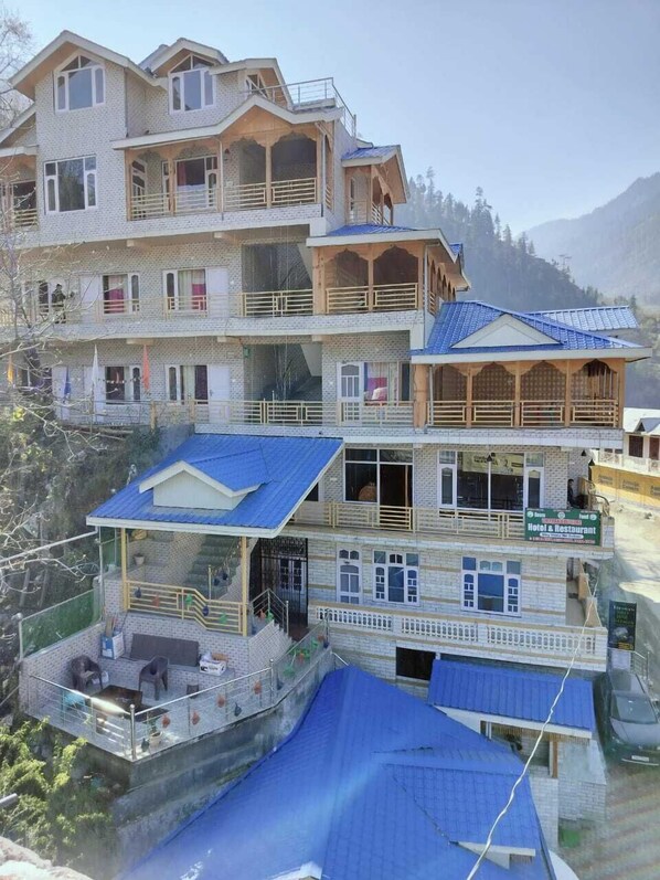 Un hôtel à plusieurs étages, doté de balcons et d’un restaurant situé au rez-de-chaussée.