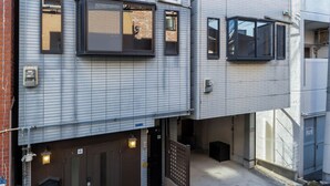 Un edificio moderno a più piani con facciata a griglia, numerose finestre e ingresso chiuso da cancello.
