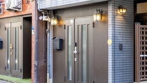 Un edificio con due ampie porte, una piccola cassetta delle lettere e due luci a parete.