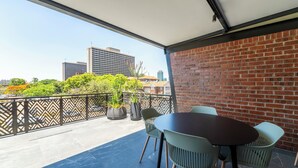 A balcony with a brick wall, a table with chairs, and potted plants. - 258 Hotel (Harare)