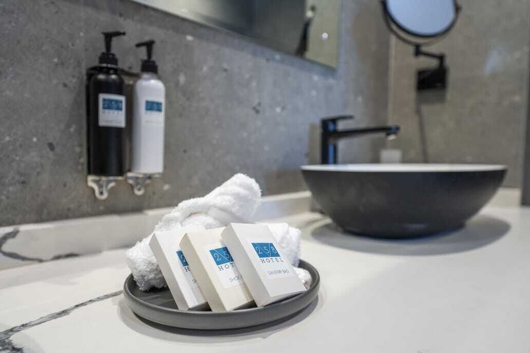 A bathroom with a marble countertop, a large sink, and toiletries on a tray.