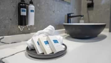 A bathroom with a marble countertop, a large sink, and toiletries on a tray.