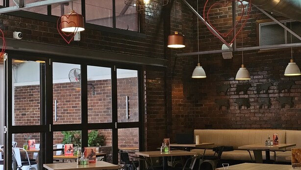 A restaurant interior with brick walls, large windows, and multiple tables and chairs. - 258 Hotel (Harare)