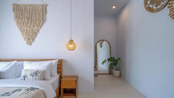Een slaapkamer met een bed, nachtkastje en een macramé wanddecoratie.