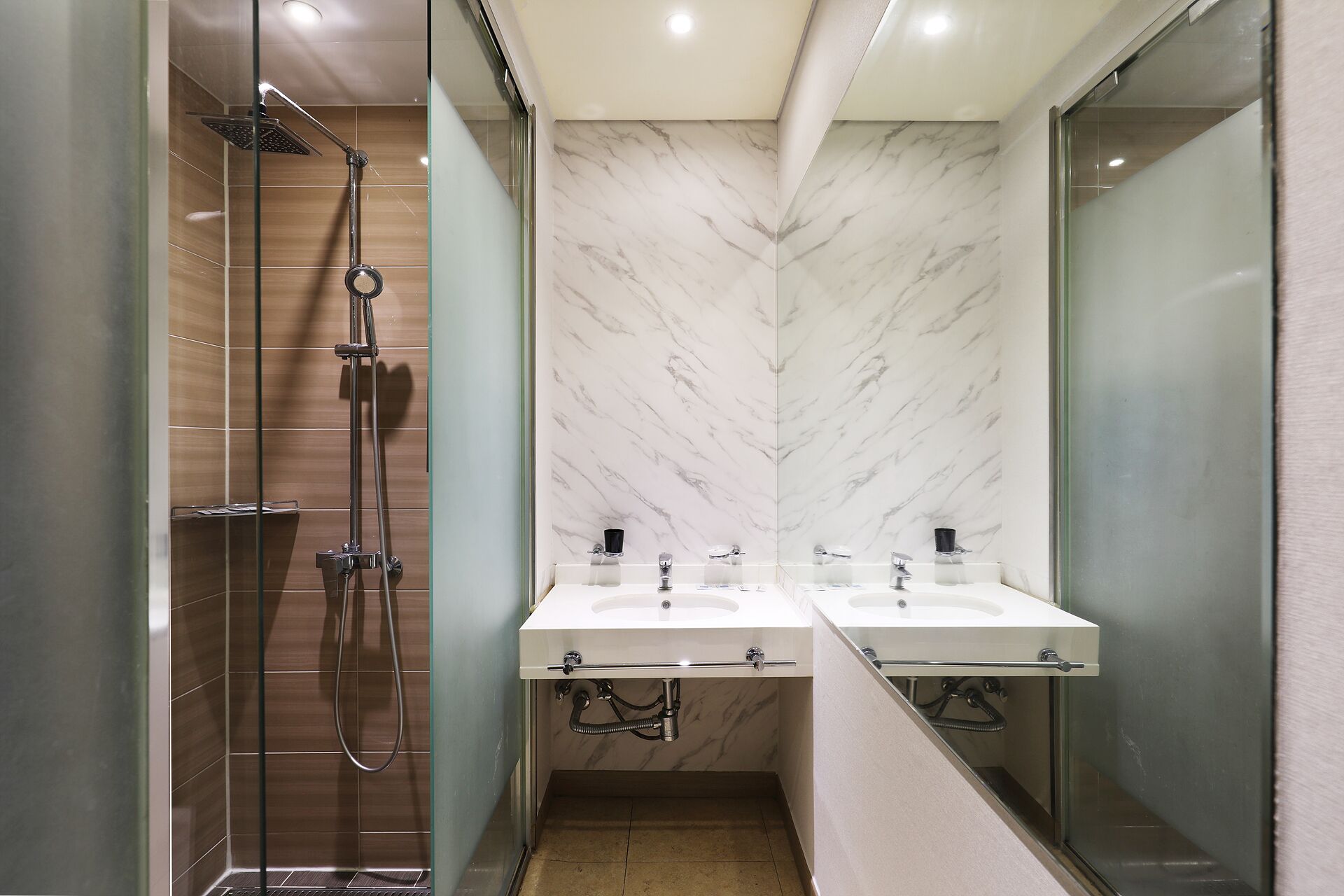 A modern bathroom with a glass-enclosed shower, two sinks with mirrors, and a marble backsplash.