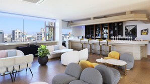 Een moderne woonkamer met een bar, grote ramen en uitzicht op de stad.