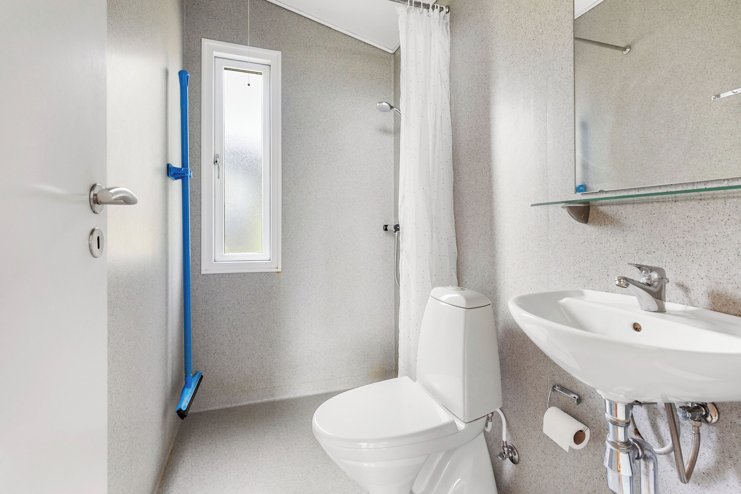 A bathroom with a white toilet, a glass shower enclosure, a white sink, and a mirror above the sink.