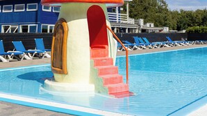 Une piscine dotée d’une structure de jeux en forme de champignon et d’un drapeau.