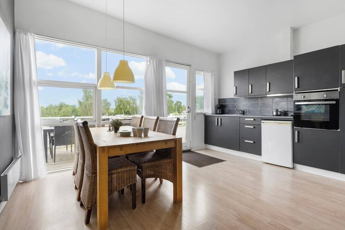 Una cocina moderna con armarios oscuros, un refrigerador blanco y un ventanal con vistas a zonas verdes.