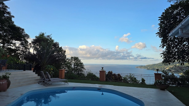 Una piscina con vistas al mar y un balcón.