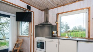 A modern kitchen with wooden walls, a large window, and a built-in oven.