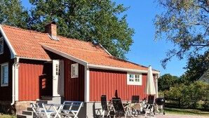 A red wooden house with a tiled roof, a porch with outdoor seating, and a grill. - 6 Person Holiday Home in Hagby (Ljungbyholm)